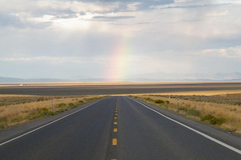 rural road with rainbow in sky