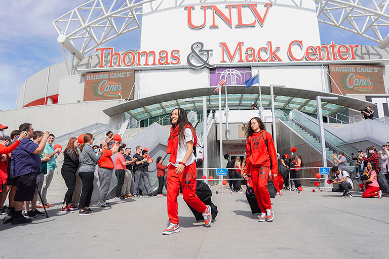 U-N-L-V Lady Rebels basketball team leaving the Thomas and Mack Center for the national championship tournament. A crowd is around them to cheer them on.