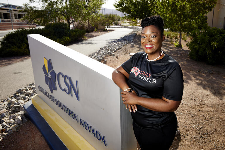 woman in UNLV shirt in front of CSN sign