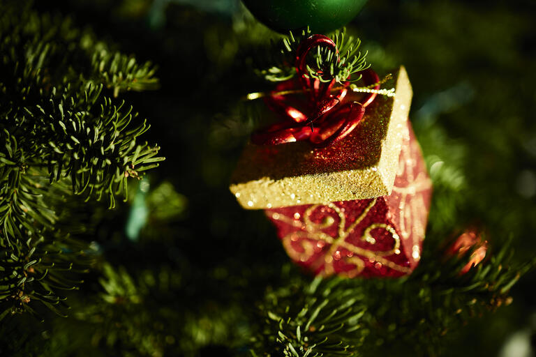 gift box ornament on lit Christmas tree