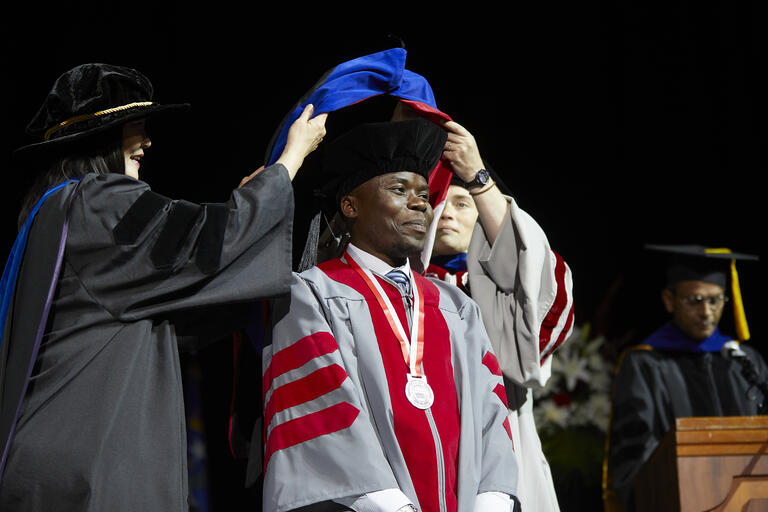 Ph.D. engineering graduate George William Kajjumba is hooded during the Spring 2022 commencement ceremony