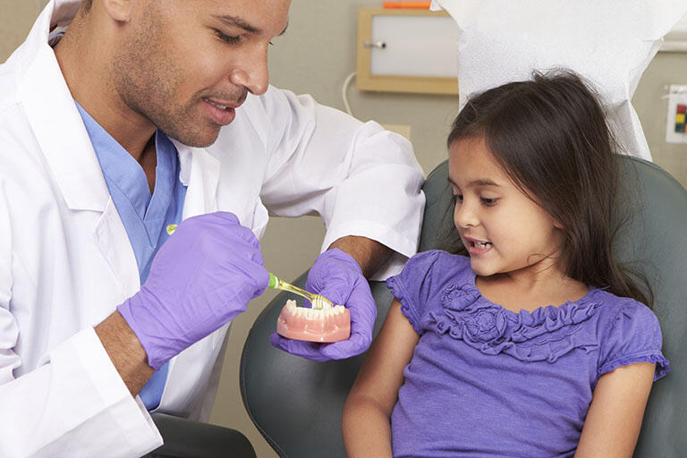 Pediatric Dentist showing a young patient a model of teeth