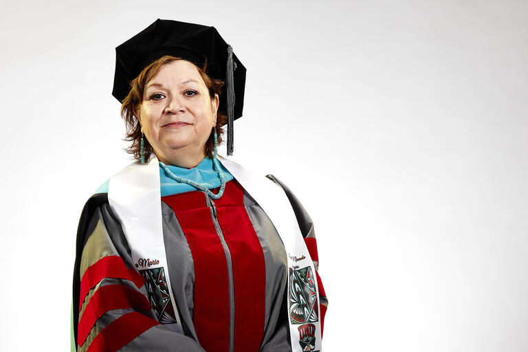 woman in doctoral graduation gown and cap with stoll decorated with Native American and UNLV school symbols