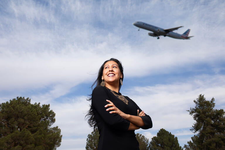 woman with arms crossed to chest as plane flies overhead