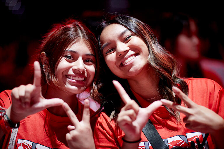Two young women smiling and forming L.V. with their fingers
