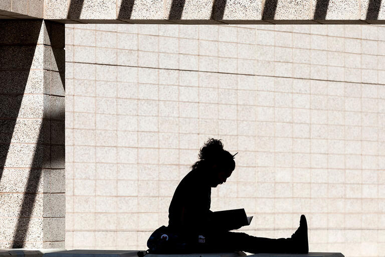 silhouette of a person sitting on ground and reading