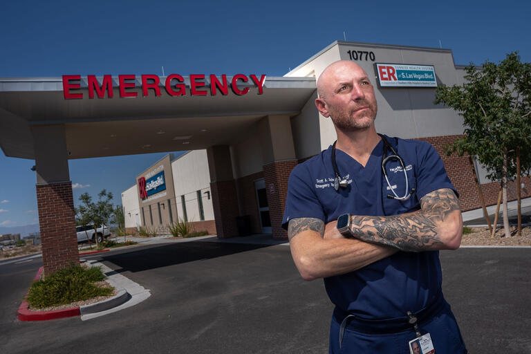 man with arm tattoos standing in front of medical emergency facility