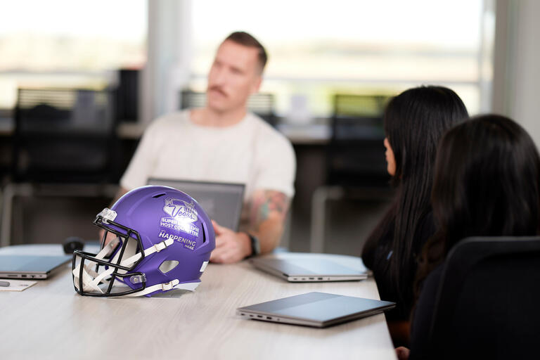 UNLV Super Bowl interns discussing at a table around the Super Bowl Host Committee Helmet.