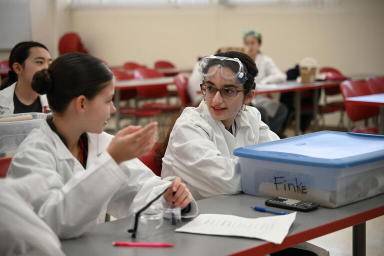 Two young students wearing lab coats and goggles during the Nevada Science Olympiad, hosted at UNLV.