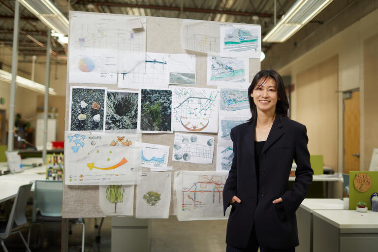 woman in front of board pinned with architecture designs