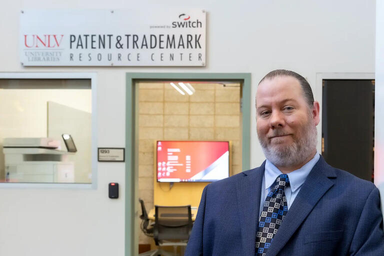 man posing below sign saying UNLV Patent &amp; Trademark Resource Center