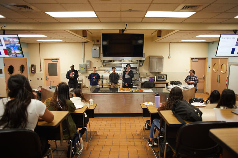 group of students watching instructor in a kitchen