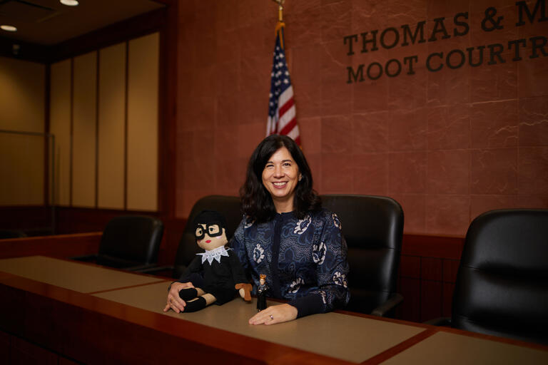 woman in courtroom holding Justice Ruth Bader Ginsburg doll
