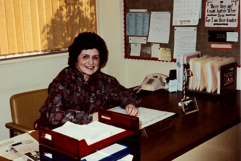 archival photo of a woman sitting behind desk