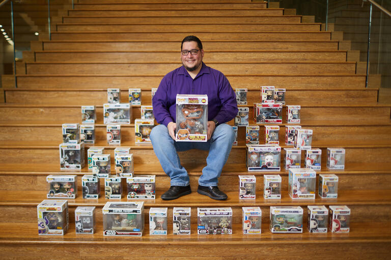 man sits on steps surrounded by boxes of Funko Pop characters