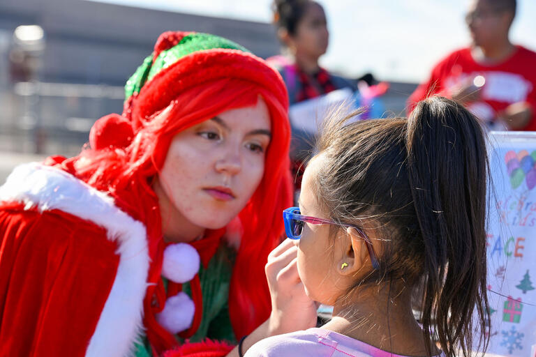 woman in elf clothing painting a child's face