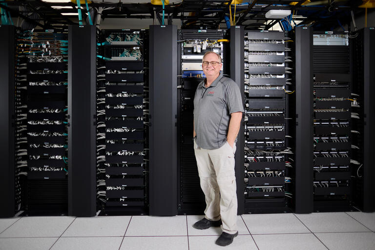 man standing in front of a row of black network servers