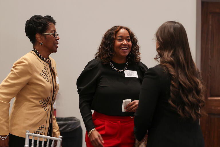 Three women talking to each other during an event.