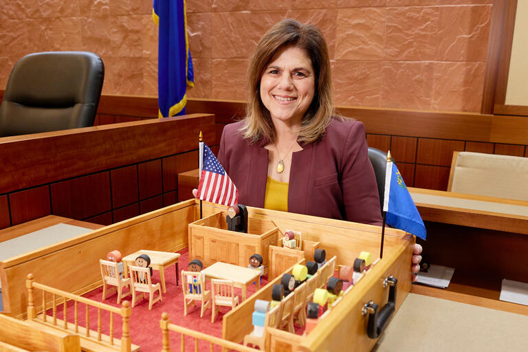 woman sitting at desk with model of courtroom in front of her