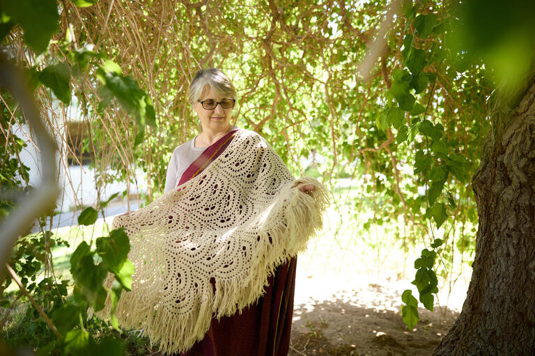 woman under trees holding white shawl
