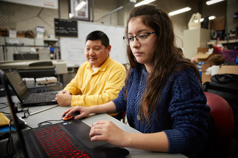 instructor working with student on computer