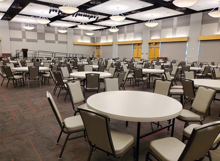 A ballroom with sets of tables with seven chairs