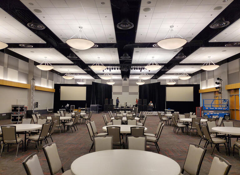A ballroom with sets of tables with seven chairs