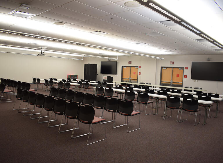 A meeting room with rows of tables and chairs