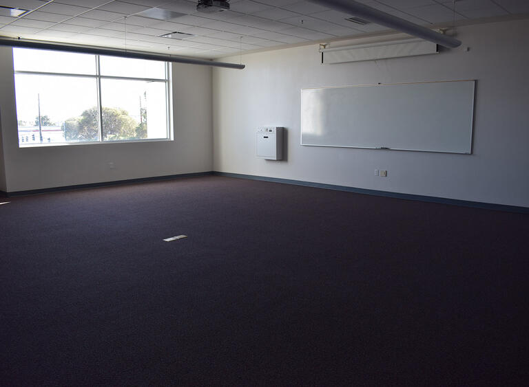 An empty classroom with a window and a whiteboard