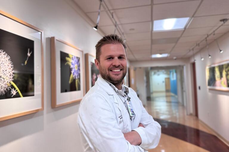 Aaron stands in hallway wearing white jacket