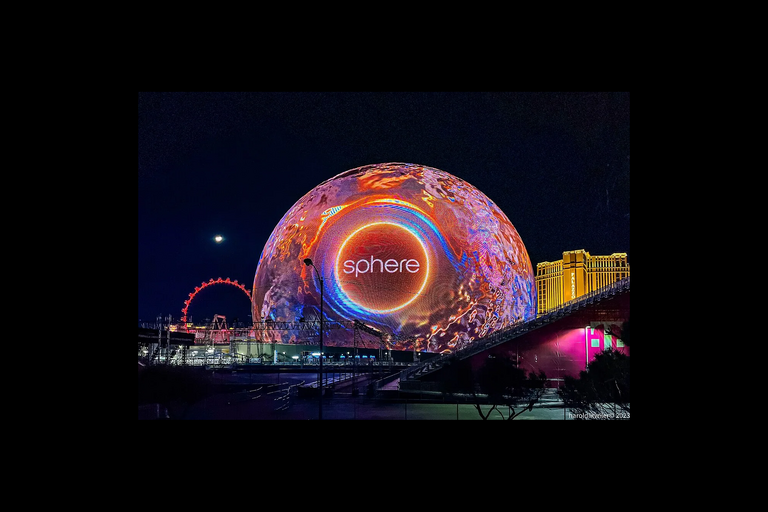the Las Vegas Sphere at night in multicolor and says &quot;Sphere&quot;