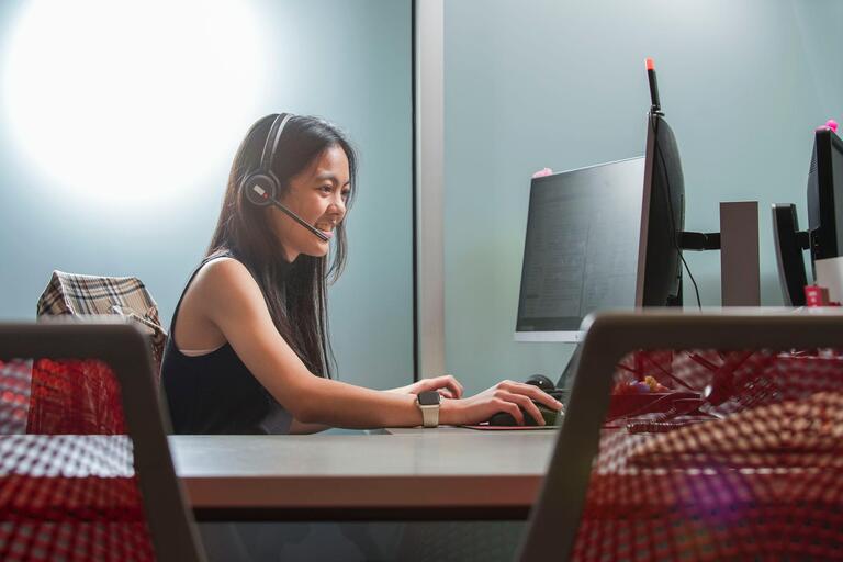 A student wearing a headset while working on a computer.
