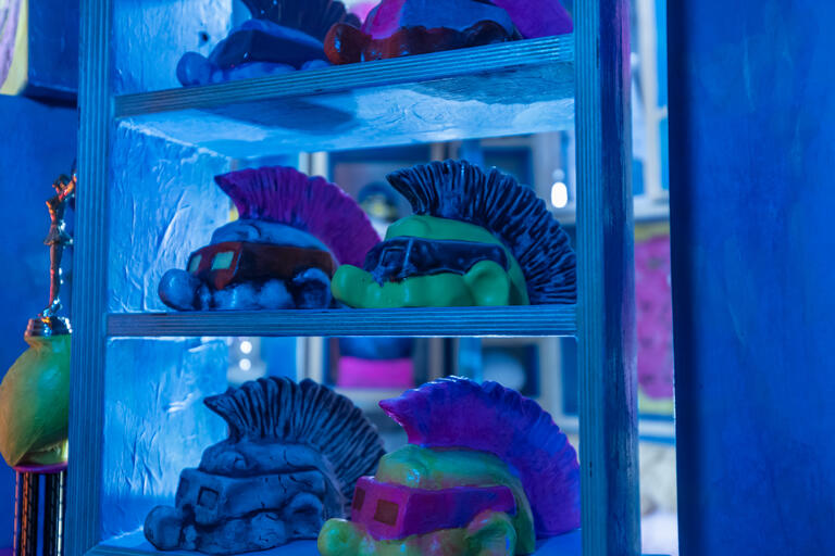 figures part of an installation showing tops of ceramic heads with mohawks