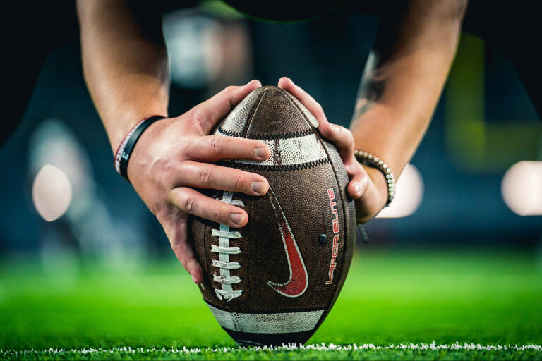 A closeup of a football between a football player's hands.