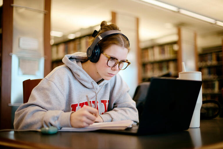 A student wearing a UNLV hoodie studies with headphones on.