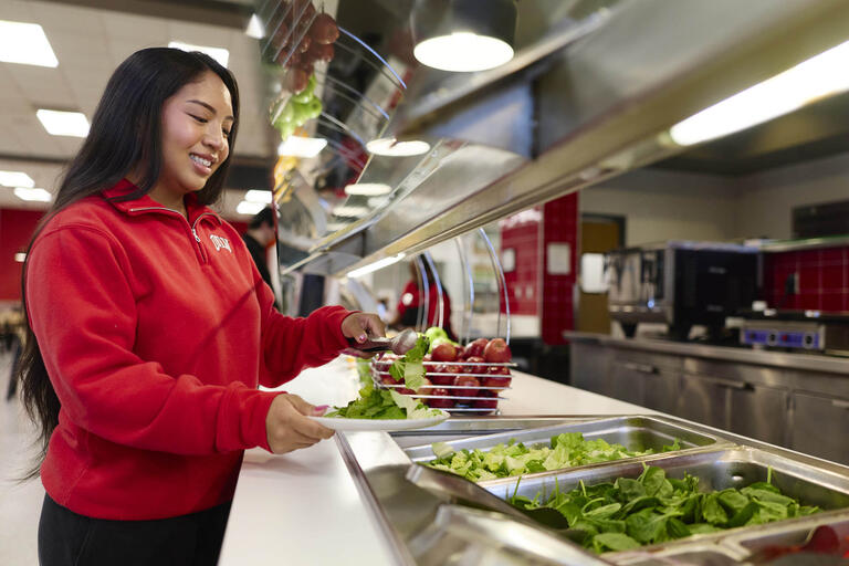 female student selecting food from salad bar