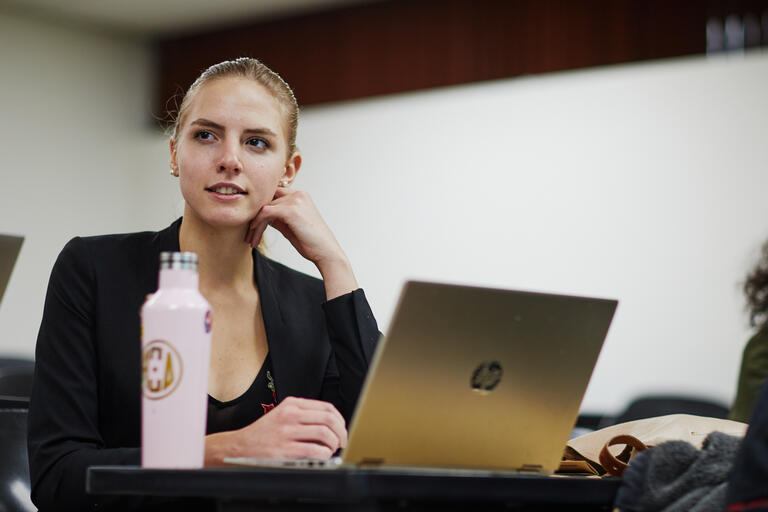 female student in business attire using computer in class
