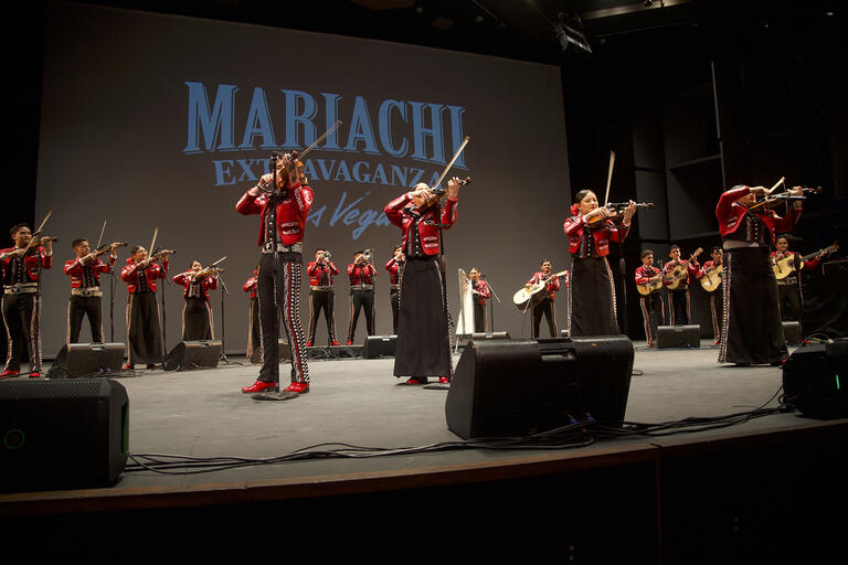 group of mariachi performers on a stage in red and black attire