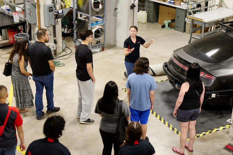 student shows members of tour an autonomous vehicle