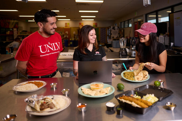 man and two women look over array of cultural cusines on tabletop