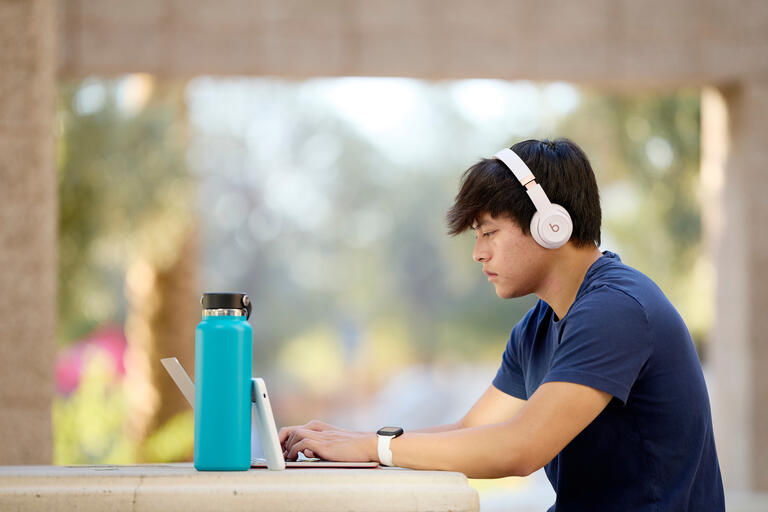 man wears headphones while typing on a tablet
