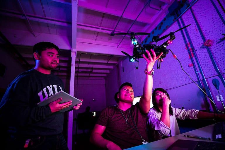 Three students work with a drone