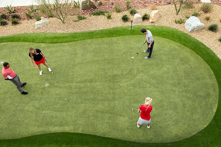 Students using a small putting green to practice putting technique.