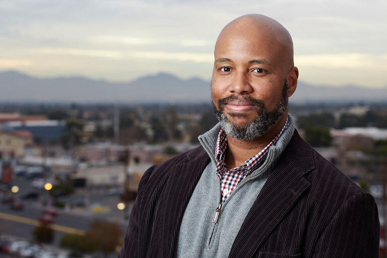 Male professor smirks against the cityscape