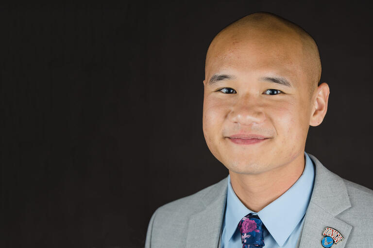 Portrait of Andrew Ho wearing a suit and tie and a UNLV pin