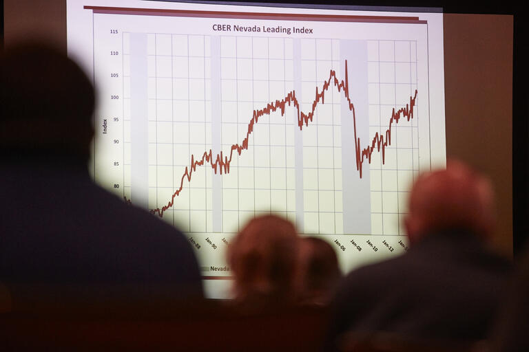 Image of economic chart projected on screen with onlookers