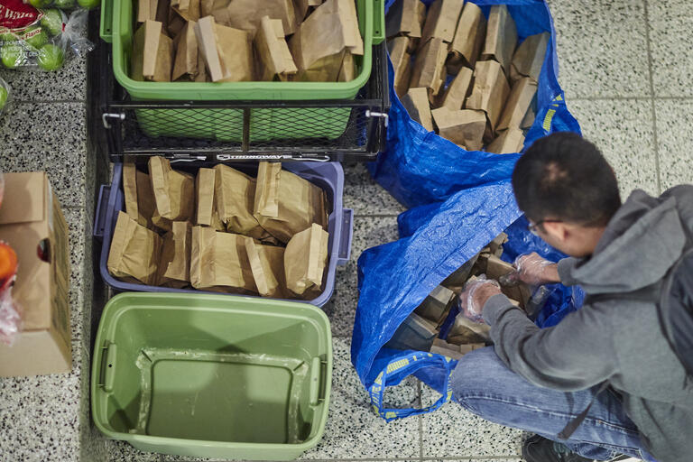 A UNLV student adds packed lunches to a crate.