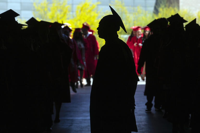 students in cap and gown line up for graduation ceremony