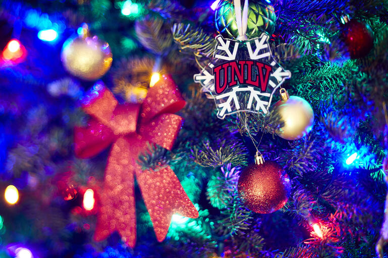 UNLV logo on Christmas tree snowflake ornament adorning colorful tree