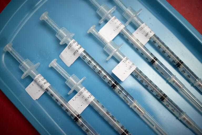 Six COVID vaccines on a blue tray